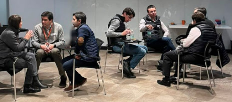 Participantes sentados en grupos pequeños conversando y analizando un caso