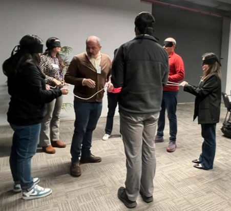 Participantes con los ojos vendados resolviendo un desafío de grupo con una cuerda